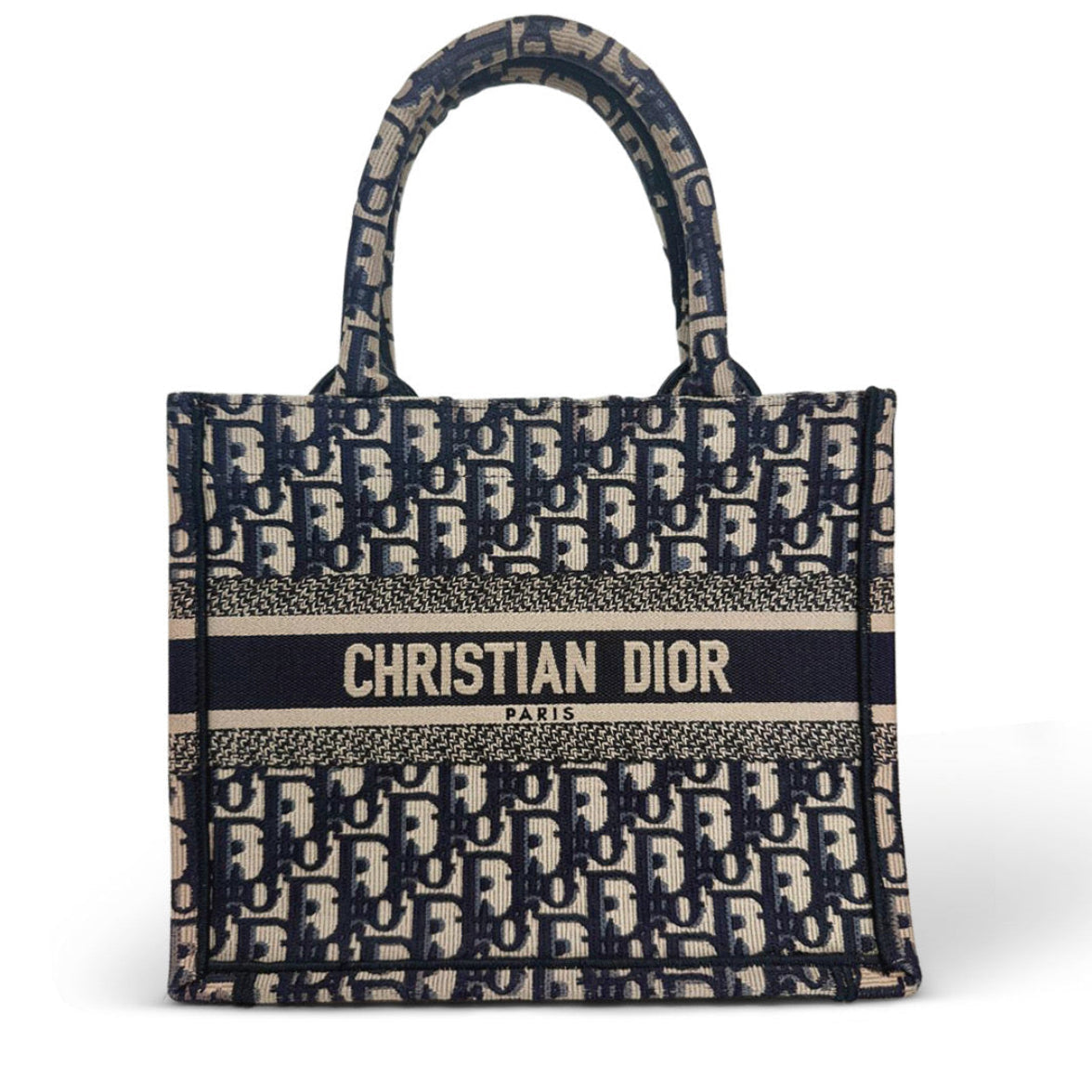 Christian Dior Oblique canvas tote bag in navy blue and beige, featuring a central black stripe with 'CHRISTIAN DIOR PARIS' in white text and dual top handles.